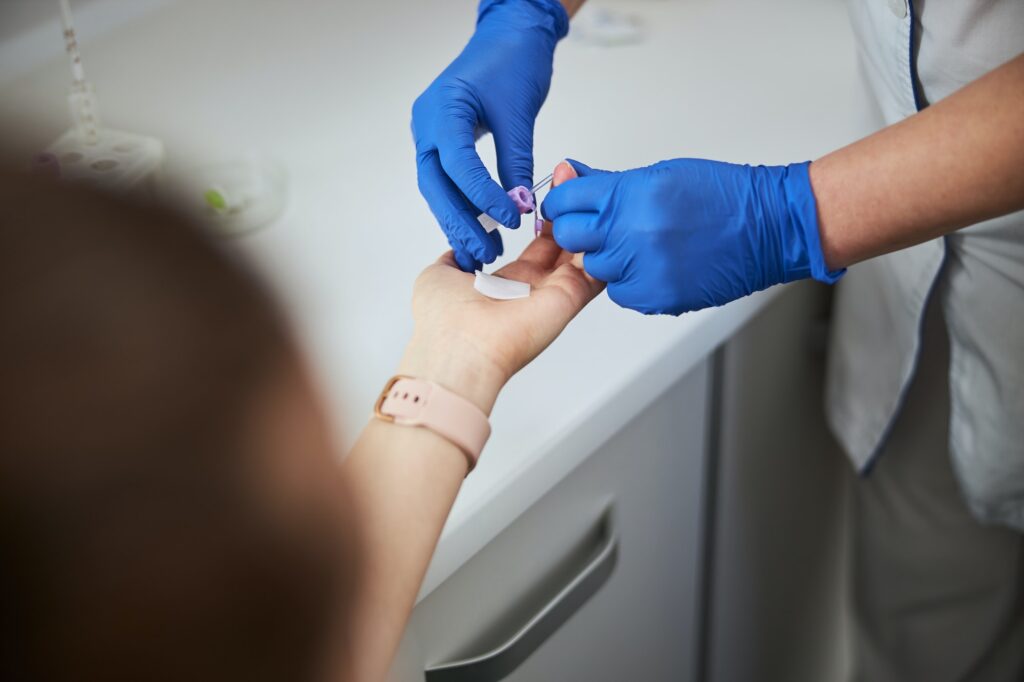 Nurse using a finger prick method for a hematological test