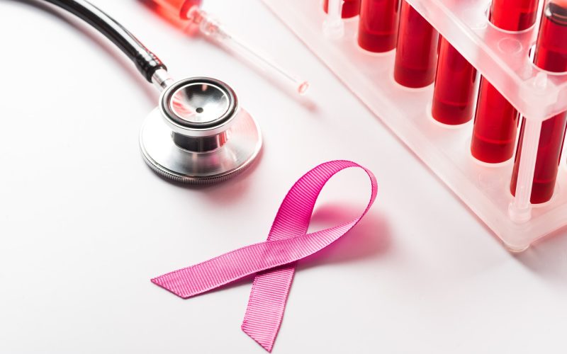 close up of Breast Cancer Awareness Ribbon, stethoscope and flasks with blood